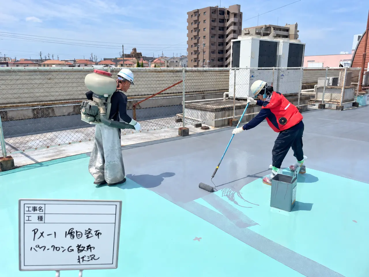 床面へのローラー塗布と防滑材の散布を行う作業員
