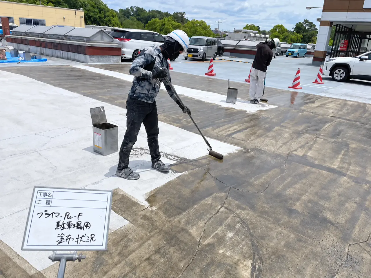 屋上駐車場の下地にローラーでプライマーを塗布する作業